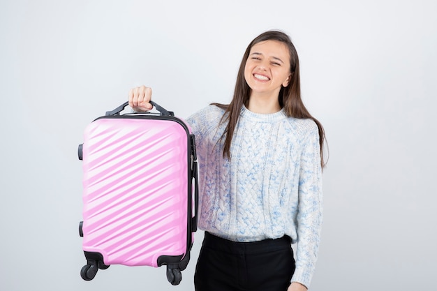 Young female traveler tourist with pink suitcase waiting for destination.