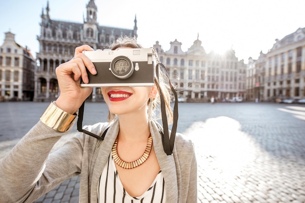 Photo young female traveler with photocamera on the central square of the old town in brussels during the morning