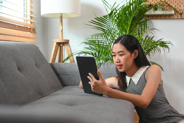 Молодая женщина использует цифровой планшет и проводит свободное время дома
