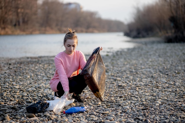 Foto giovane volontaria che raccoglie la spazzatura sul fiume
