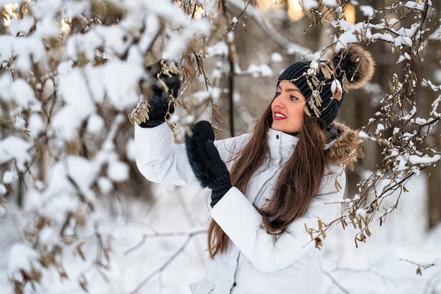 Giovane donna che cammina nella giornata invernale innevata all'aperto, sfondo del paesaggio della foresta invernale