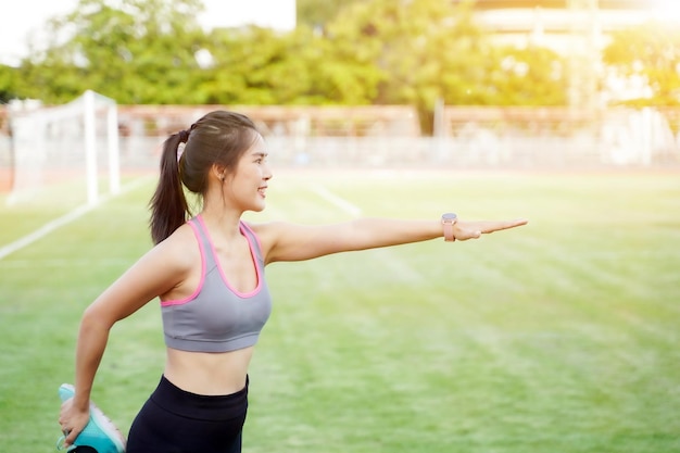 Young female warm up outdoor morning at the football stadium with sun flare