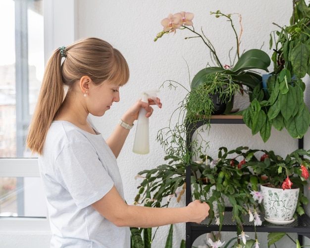 バルコニーに若い女性の水やり植物や花。鉢植えの植物の世話をする緑の親指庭師