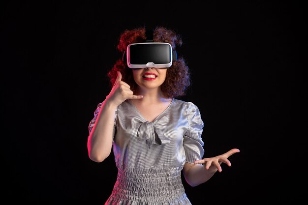 Young female wearing virtual reality headset on a dark surface