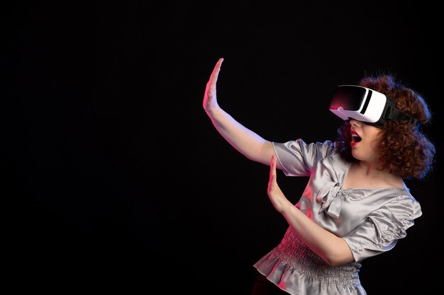 Young female wearing virtual reality headset on dark surface