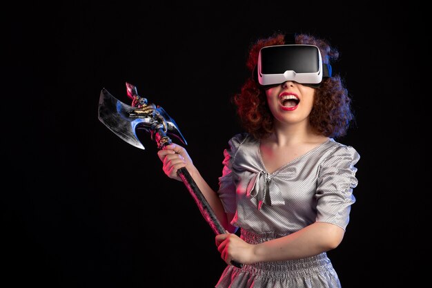 Young female wearing vr headset with battle axe on a dark surface