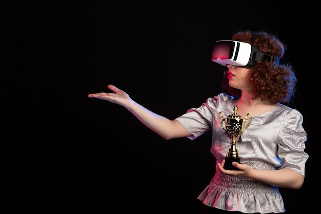 Young female wearing vr headset with cup on dark surface