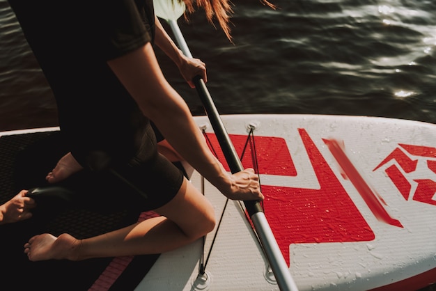 Young Female In Wetsuit Rowing Surf With Paddle.