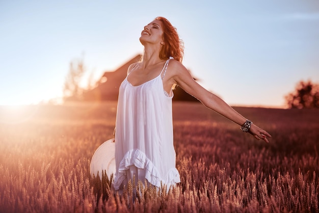 Young female in white dress standing in a wheat field