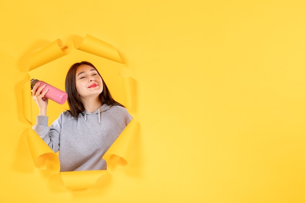 young female with bottle of water on a torn yellow paper background gym athlete fit indoor