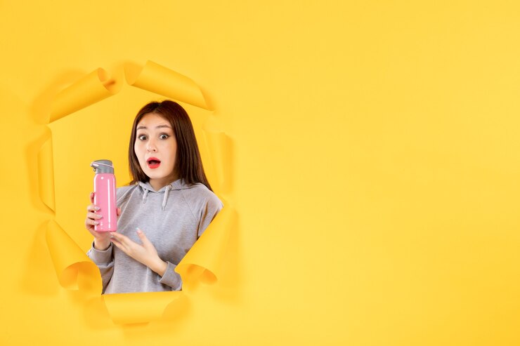 Photo 年轻的女人用水瓶在撕裂的黄色纸背景健身房适合室内