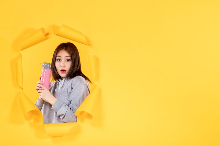 Photo 年轻的女性用水瓶在撕裂的黄色纸上背景健身房室内运动员