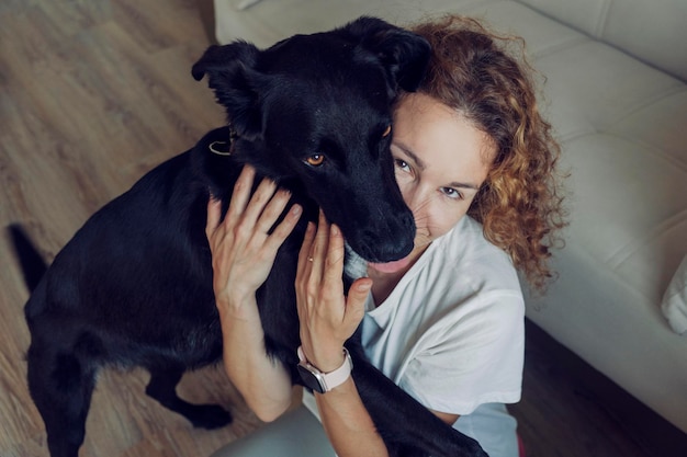 Photo young female with curly hair and cute black dog high quality photo