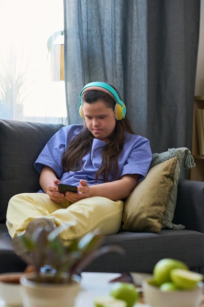 スマートフォンの画面を見ているヘッドフォンでダウン症の若い女性