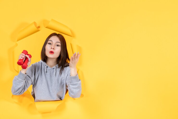 Photo 年轻的女性用<unk>杆在撕裂的黄色纸背景运动适合健身房运动员