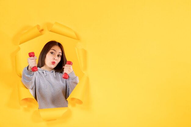 young female with dumbbells on yellow background gym athlete fit