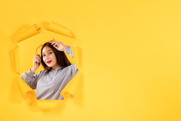 young female with headphones on torn yellow paper background ultrasound audio