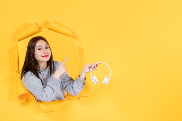 young female with headphones on the torn yellow paper background ultrasound music sound audio