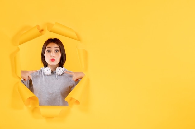 young female with headphones on a yellow paper background sound ultrasound audio