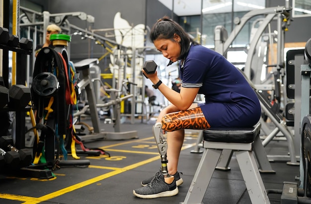 Photo young female with one prosthetic leg warms up by lifting light weights concept of living a womans