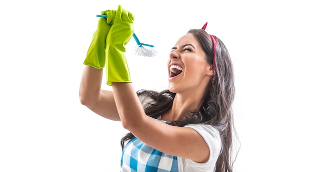 Young female with rubber gloves on isolated background singing wildly into a kitchen brush.