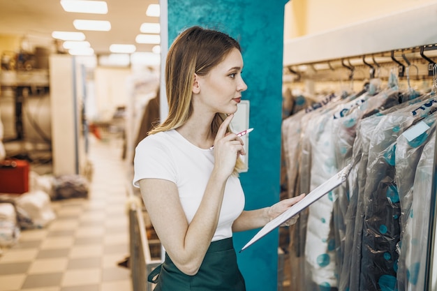 Young female worker in dry-cleaning salon.