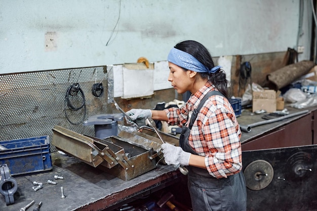 Young female worker of industrial plant choosing huge wrench for repair work