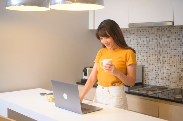 彼女のラップトップで働いて、一杯のコーヒー、ライフスタイルとビジネスコンセプトを持っている若い女性