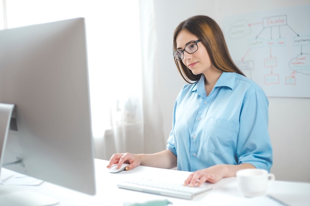 Young female works on computer sitting in office. Business woman manager at the workplace.  