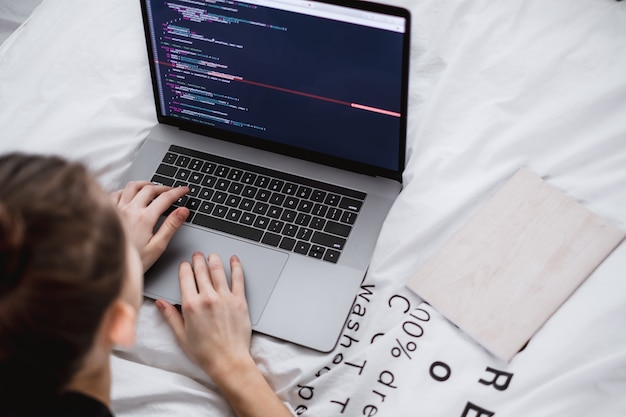 Foto la giovane femmina scrive il codice del programma su un computer portatile