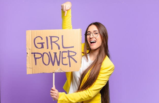 Young feminist businesswoman holding board with girl power text