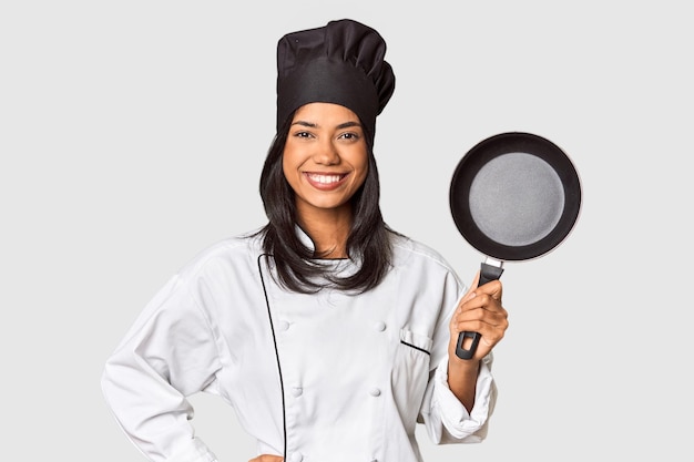 Young Filipina chef holding pan by handle showing a copy space on a palm