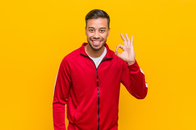 Young filipino fitness man cheerful and confident showing ok gesture.