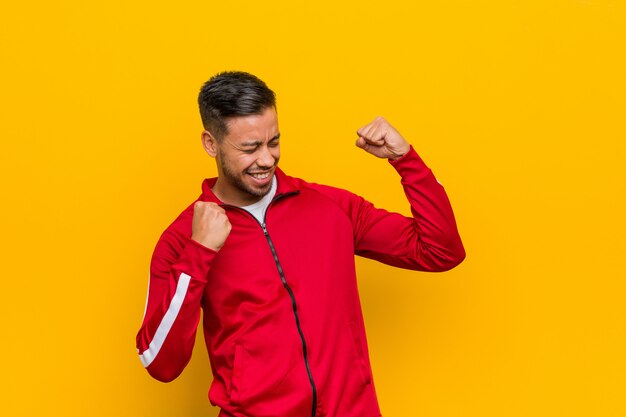 Young filipino fitness man raising fist after a victory, winner concept.