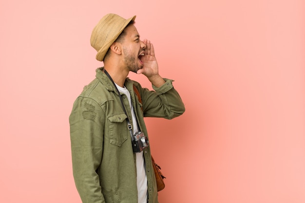 Young filipino traveler man shouting and holding palm near opened mouth.