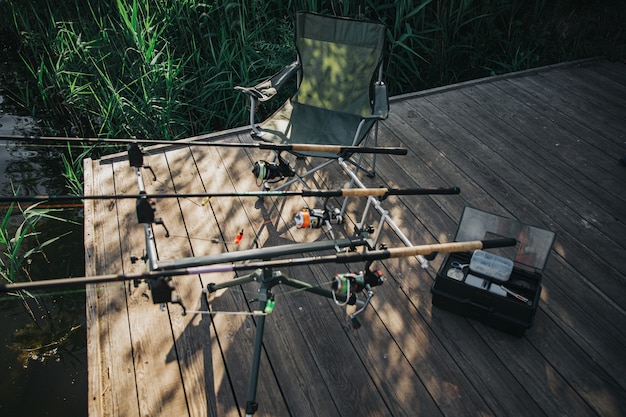 Young fisherman fishing on lake or river. Picture of fishing rods on river or lake shore. Empty place without people. Full equipmentfor fishing. Sunny day.