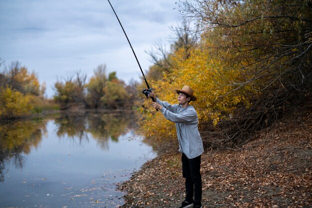 Молодой рыбак в шляпе рыбалка с жезлом в лесное озеро F