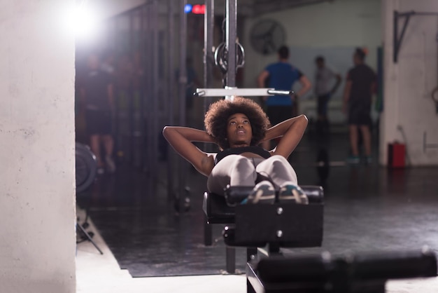 Giovane donna afroamericana in forma che fa sit up in palestra presso la palestra. esercizi addominali siediti