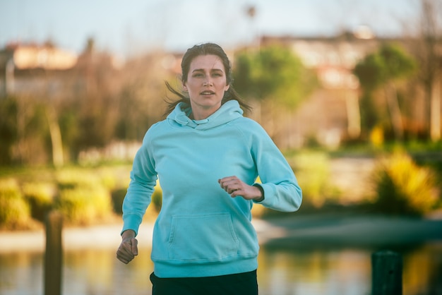 Young fit blonde woman running in the park