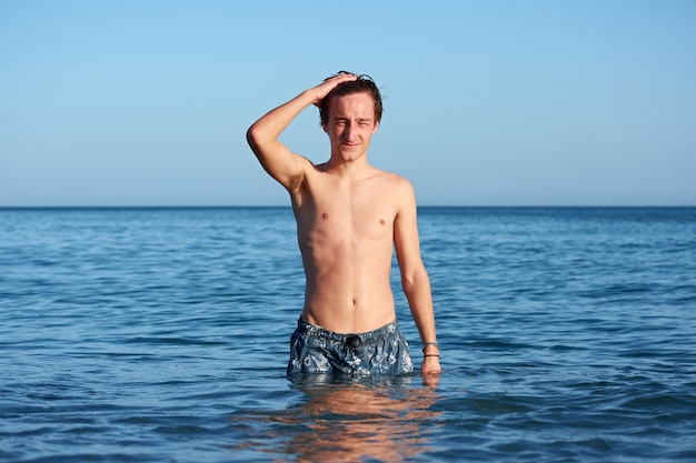 A young fit caucasian male posing and touching his hair in the sea