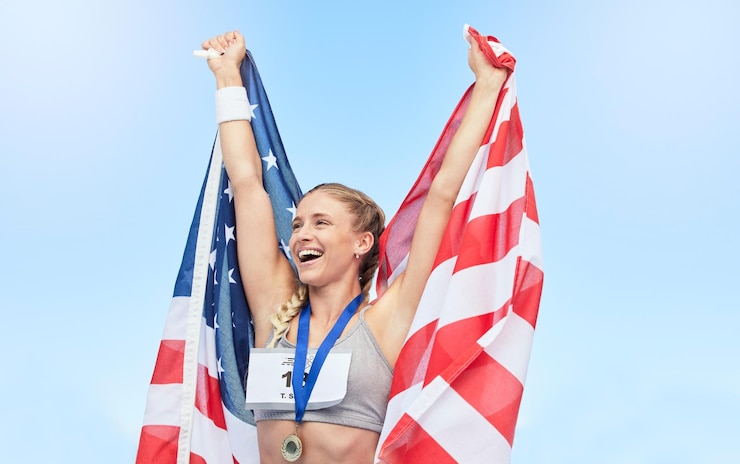 Photo young fit female athlete cheering and holding american flag after competing in sports smiling fit active sporty woman feeling motivated and celebrating achieving gold medal in olympic sport
