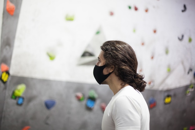 Photo young fit male climber wearing mask on steep rock indoors