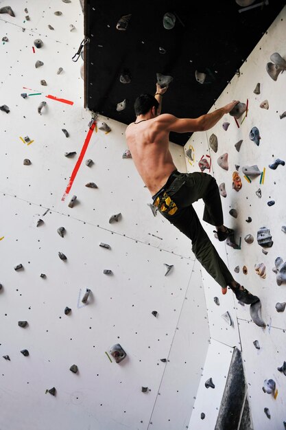 젊고 건강한 남자는 실내 연습 벽에서 무료 등산을 운동합니다.