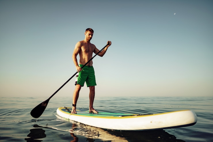 Photo 湖に浮かぶパドルボードの若いフィット男