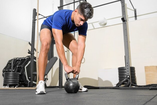 Giovane uomo in forma che si allena con i kettlebell