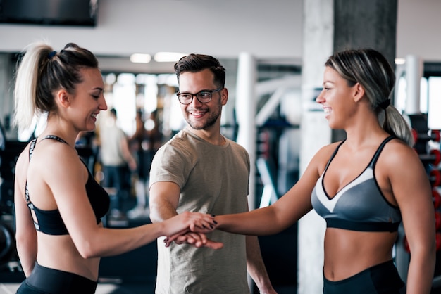 Young fit sports people putting hands together in the gym.