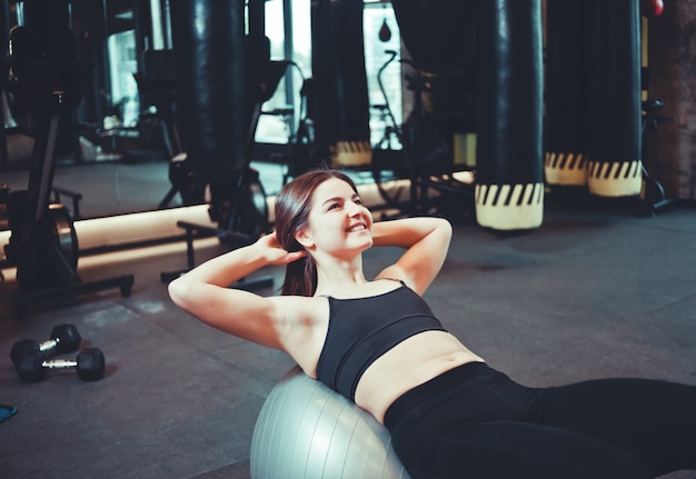 Young fit woman doing abs crunches on fitball.