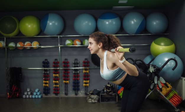 Young fit woman doing exercise with fitness stick in training class.