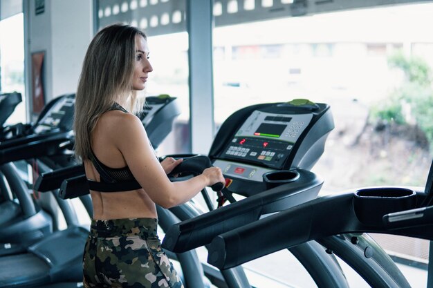 Young fit woman doing running exercise in gym at treadmill speedwalk running road.