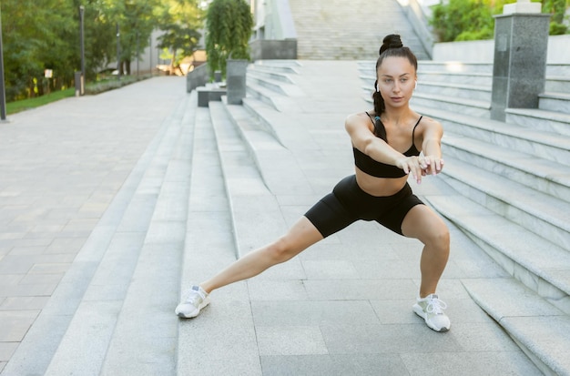 Young fit woman doing warm-up, side lunges outdoors